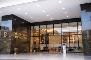 Der Eingang zum Van Phong Office Hotel mit modernem Design, großen Glasfenstern und einem gut sichtbaren Empfangsbereich.
