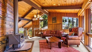 A cozy cabin interior with a fireplace, leather furniture, and large windows.