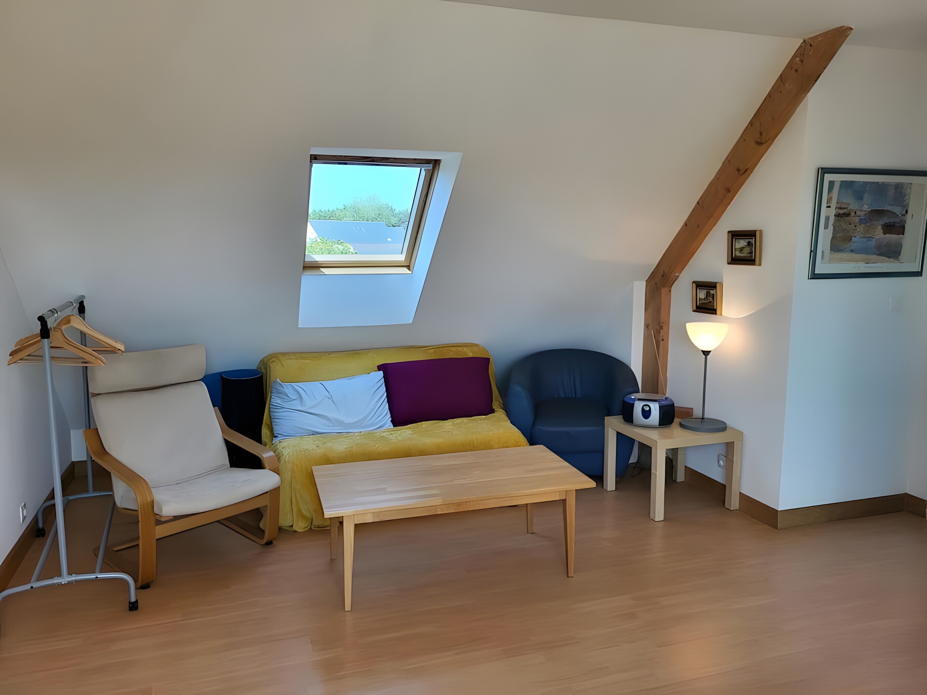 Una habitación con cama de altillo, sofá, pequeña mesa, lámpara y ventana con vistas.