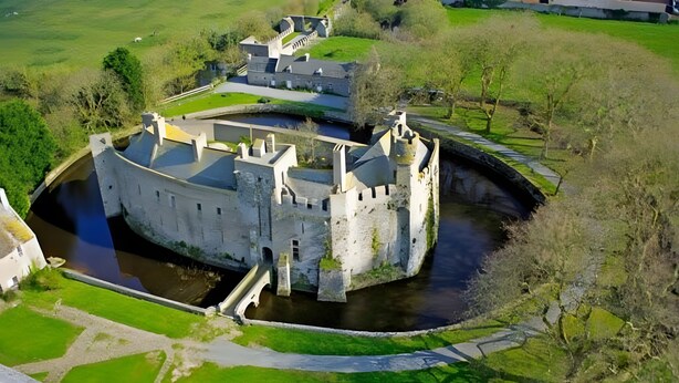 Un château médiéval doté d’un fossé, d’un pont et d’un petit cours d’eau.
