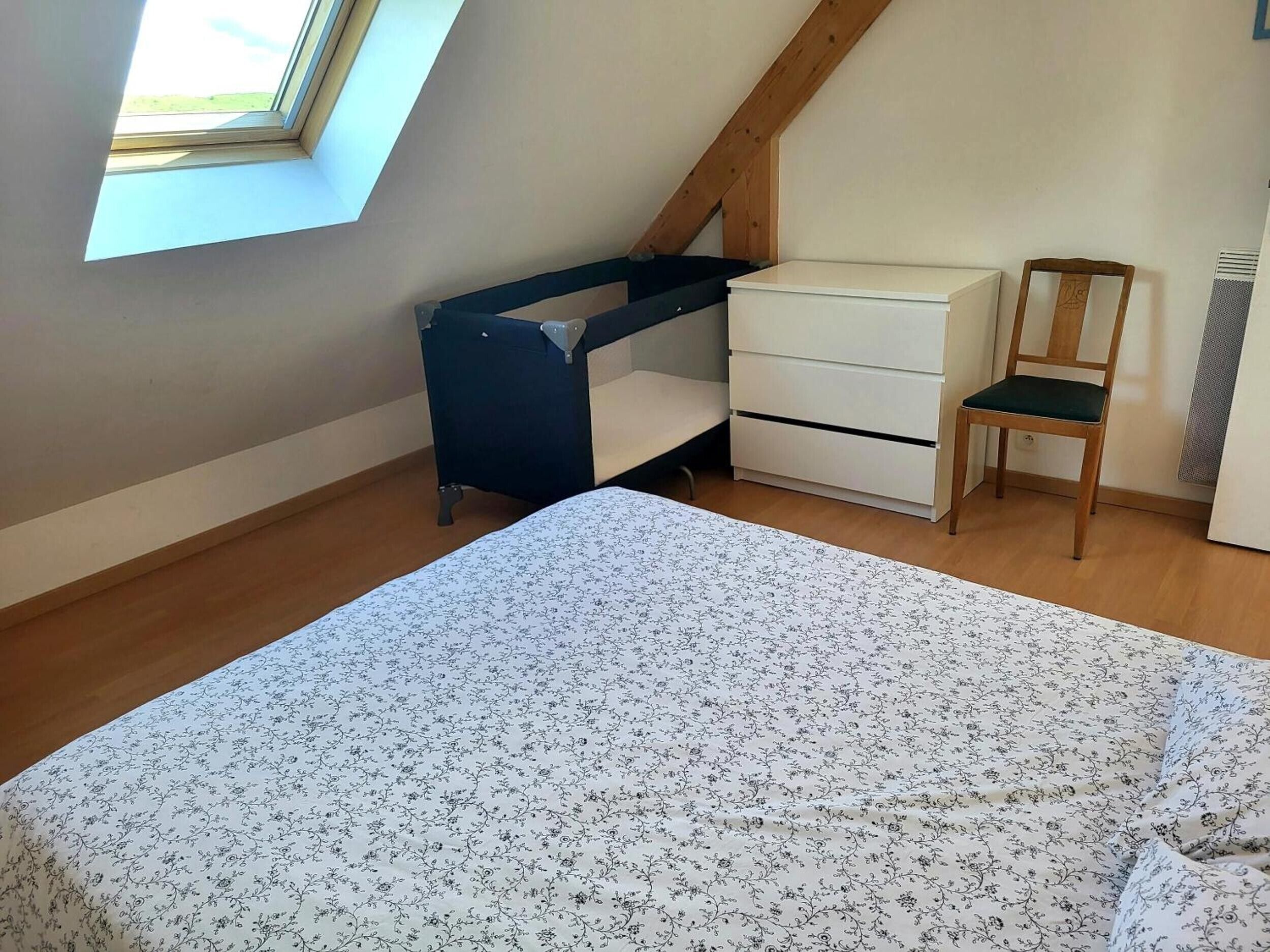 A bedroom with a bed, a desk, a chair, and a dresser.
