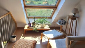 Une pièce dotée d’une lucarne, d’une petite table ornée de plantes, d’une radio et d’une chaise.
