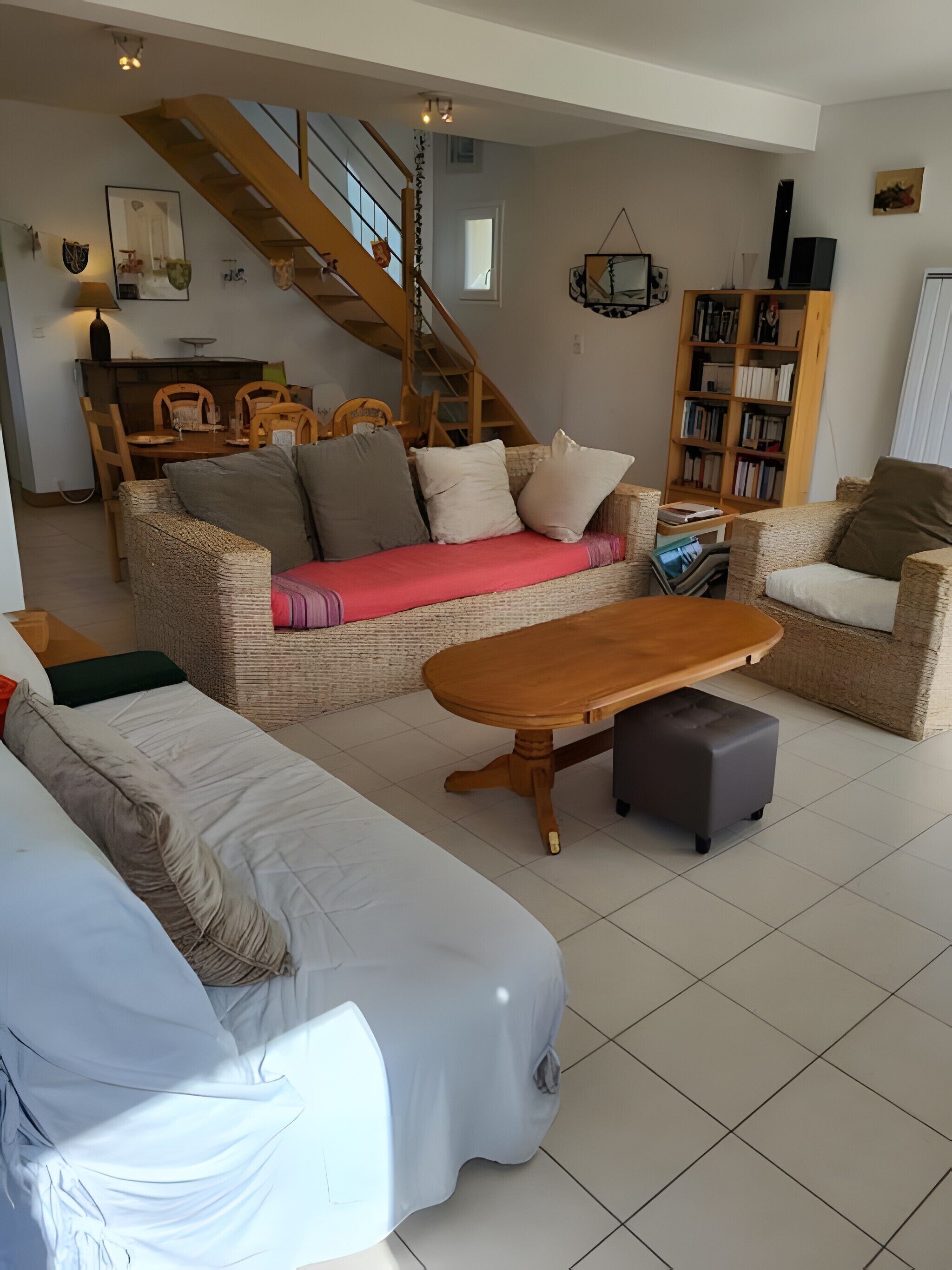 Una sala de estar con un sofá, una mesa de centro de madera, una estantería y una escalera.