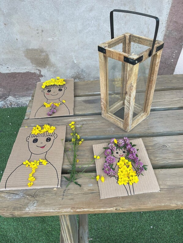 A wooden table with three cardboard cutouts of a girl with flowers, a wooden lantern, and a small plant.