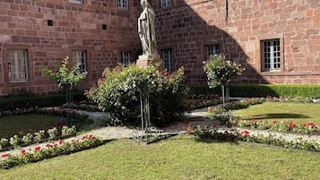 En gårdhave med en statue, stengårde og blomsterbede.