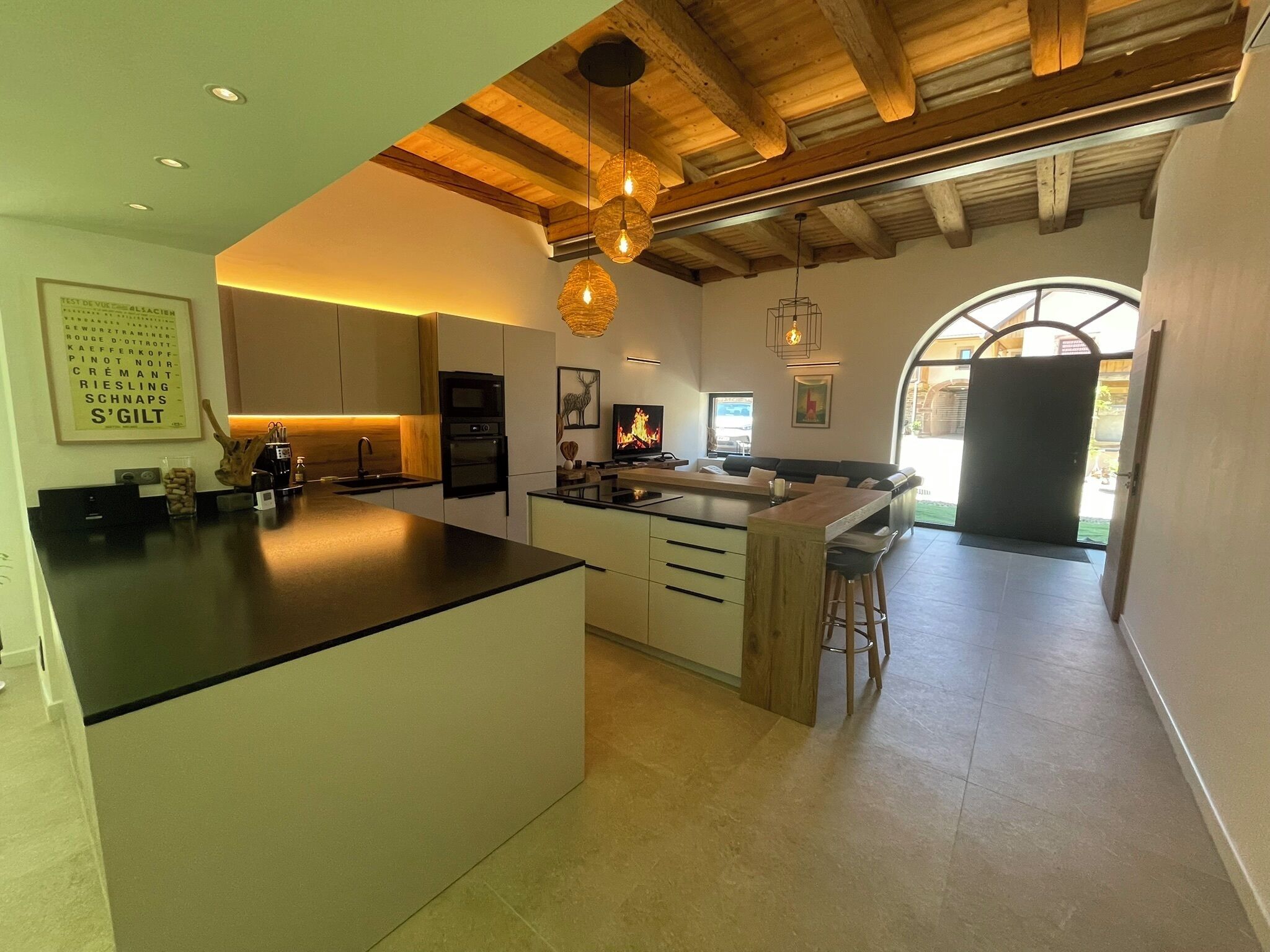 A modern kitchen with a central island, built-in appliances, and a dining area with a view.