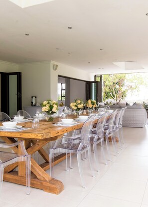 Un espace de salle à manger moderne avec une table en bois, des chaises transparentes et des centres de table floraux.