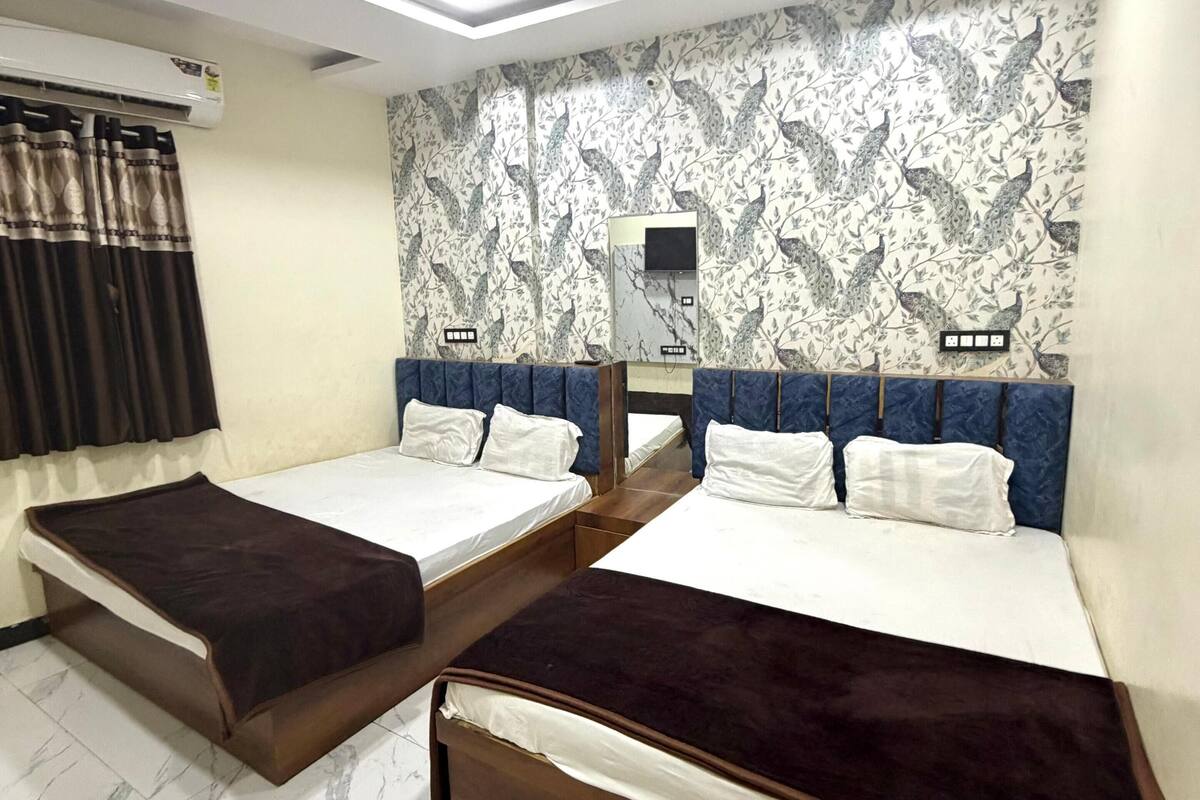 Ein Hotelzimmer mit zwei Betten, einem Deckenventilator, einer Klimaanlage und einem strukturierten Wandpapier.