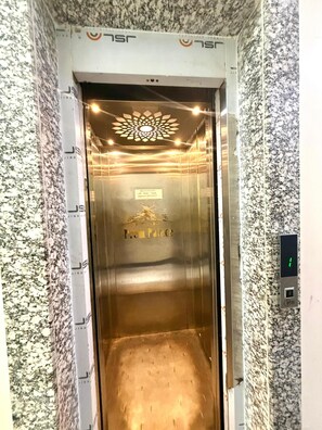 Un ascensore con interni metallici, un display digitale e un cartello che indica 'Hotel Zen Palace'.
