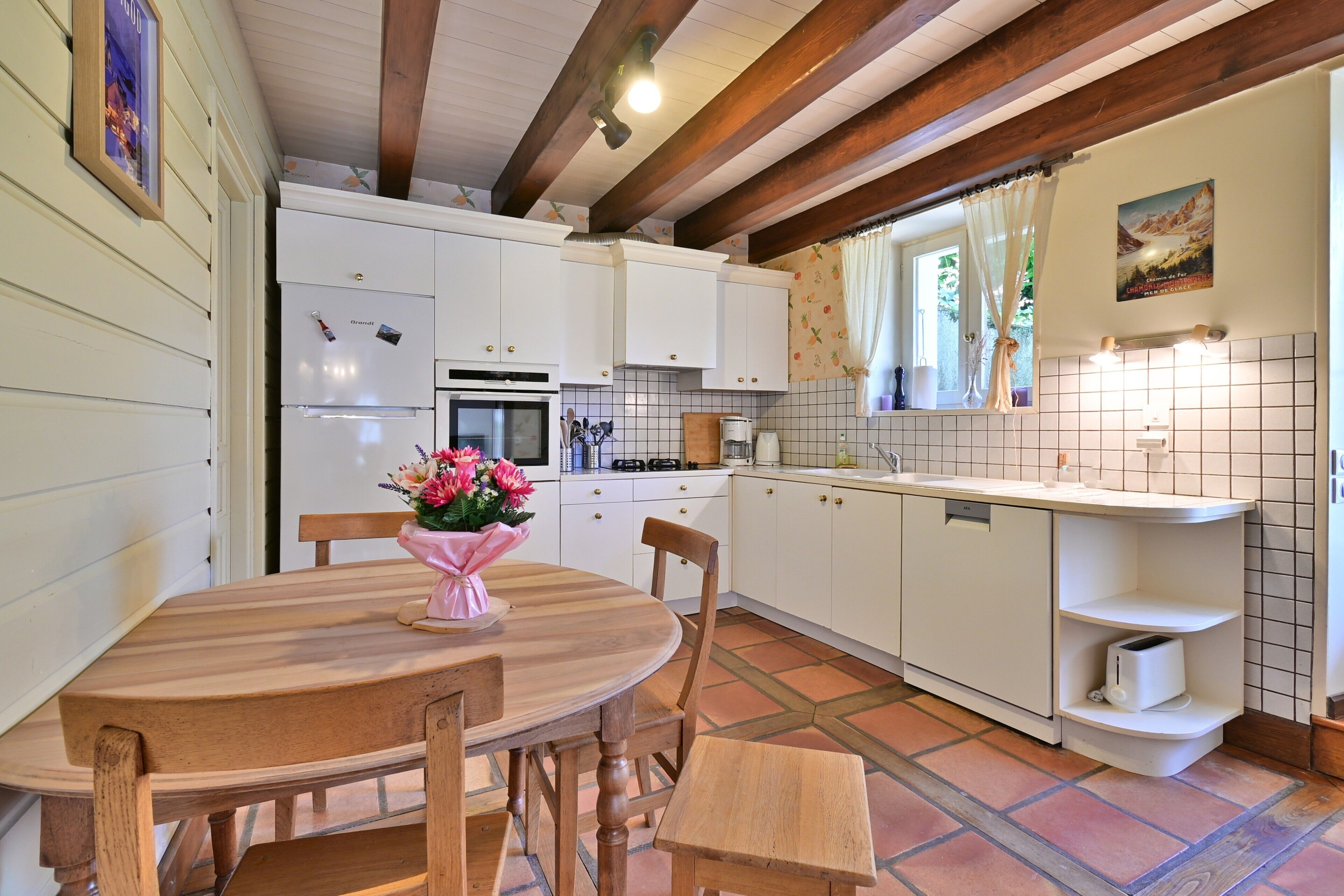 A kitchen with white cabinets, a wooden dining table, and a bench.