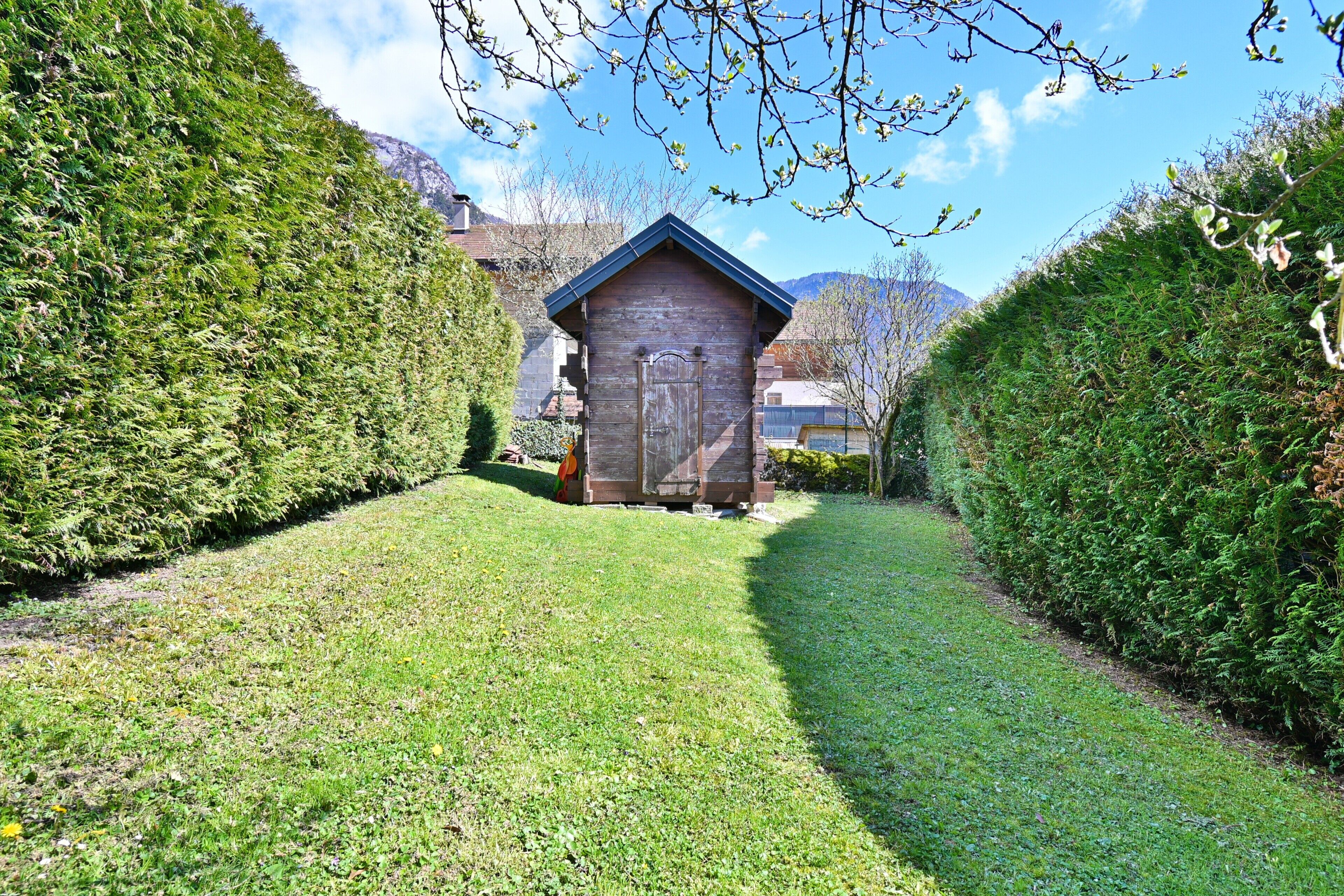 A wooden shed in a well-maintained garden with a clear path leading to it.