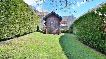 A wooden shed in a well-maintained garden with a clear path leading to it.