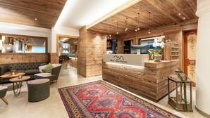 Un hall d’hôtel avec un comptoir d’accueil en bois, un canapé et un tapis à motifs.