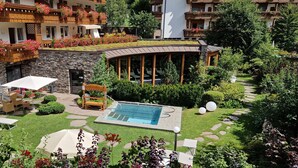 Un espace piscine avec des chaises longues, une terrasse en bois et un mur en pierre.