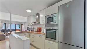 A modern kitchen with stainless steel appliances, a large island, and a view of the sea. - Apartment 'Estilo El Higuerón' with Sea View, Wi-Fi, and Air Conditioning (Benalmádena)