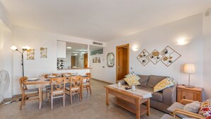 A living room with a dining table, chairs, a sofa, and a TV. - Apartment 'Estilo El Higuerón' with Sea View, Wi-Fi, and Air Conditioning (Benalmádena)