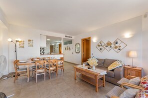 Ein Wohnzimmer mit Esstisch, Stühlen, einer Couch und einem Fernseher.