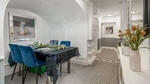 A dining area with a table set for four, blue chairs, a black tablecloth, and a checkered rug. - Chelsea 2BR Private Courtyard Earl s Court Tube (London)