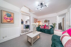 A living room with a checkered floor, a green sofa, a white coffee table, and a painting of a pineapple. - Chelsea 2BR Private Courtyard Earl s Court Tube (London)