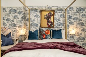 A bedroom with a four-poster bed, a chair, and a wall-mounted lamp. - Chelsea 2BR Private Courtyard Earl s Court Tube (London)