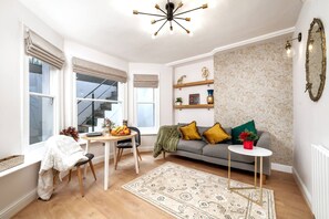 A modern living room with a dining table, sofa, and decorative items. - Kensington Chelsea 1BR Patio Apartment Tube (London)