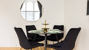 Ein Essbereich mit einem runden Tisch, vier schwarzen Stühlen und einem runden Spiegel an der Wand.