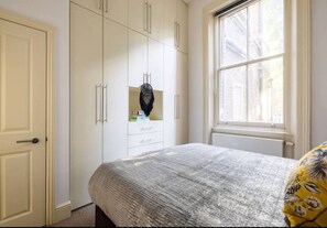 Quarto com cama, guarda-roupa, janela e porta.