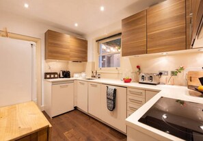 A modern kitchen with wooden cabinets, a built-in oven, and a window above the sink. - Chelsea 3BR Duplex Garden Terrace Walk to Tube (London)