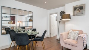 A dining area with a round table, black chairs, and a mirror on the wall. - Chelsea 2BR Garden Patio Apartment Tube (London)