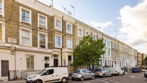 A row of terraced houses with a white van parked on the street. - Chelsea 2BR Garden Patio Apartment Tube (London)