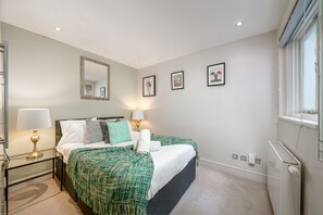 Ein Schlafzimmer mit zwei Betten, einem Spiegel, Wandleuchten und einer Heizung.