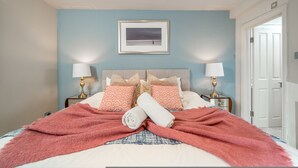 A bedroom with a bed, two bedside tables, a framed picture on the wall, and a door to the right. - Chelsea 2BR Garden Patio Apartment Tube (London)