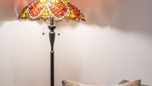 A room with a sofa, a floor lamp, and a table with a vase and decorative items. - Chelsea 2BR Garden Patio Apartment Tube (London)