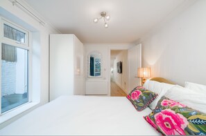 Ein Schlafzimmer mit einem großen Bett, einer Nachttischlampe, einem Spiegel und einem Fenster.