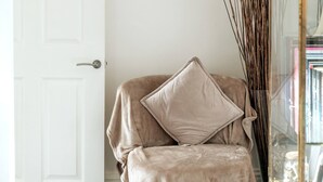 A beige chair with a cushion, a white door, and a glass cabinet with items inside. - Earl s Court Chelsea 4BR Duplex Ap Walk to Tube (London)