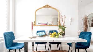A dining area with a white marble table, blue upholstered chairs, a tufted bench, and a large ornate mirror. - Earl s Court Chelsea 4BR Duplex Ap Walk to Tube (London)