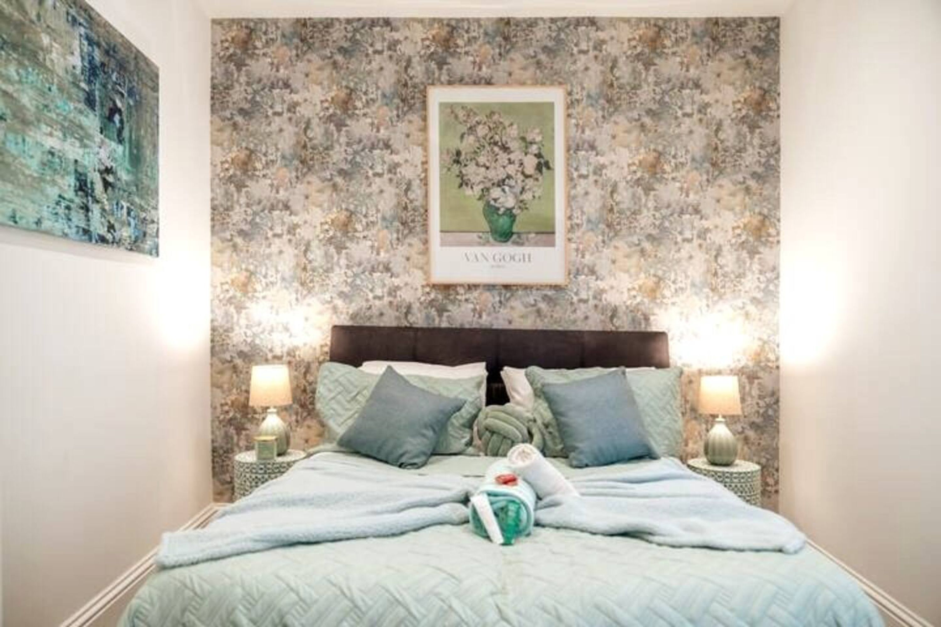Un lit avec une couette, des oreillers et un tableau encadré accroché au mur.