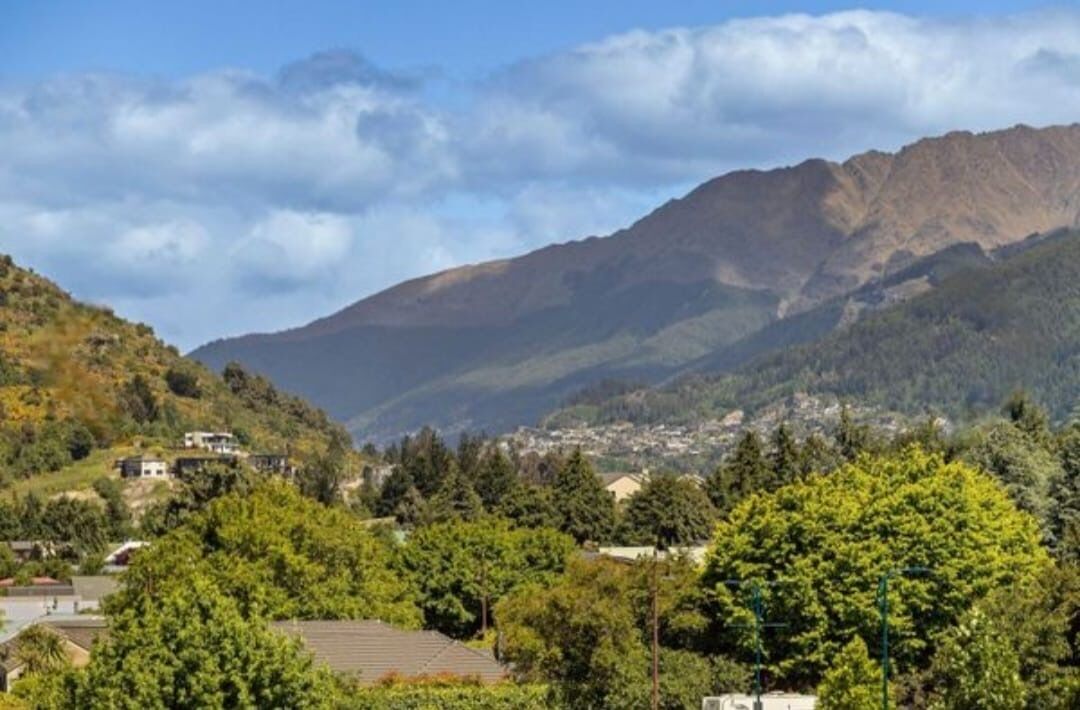 A mountainous landscape with residential buildings and dense greenery.