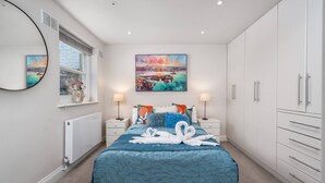 A bedroom with a bed, a painting, a mirror, a radiator, and a wardrobe. - Earl s Court Chelsea 2BR Modern Apt Walk to Tube (London)