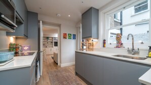 A modern kitchen with grey cabinets, a large window, and a view of the street. - Earl s Court Chelsea 2BR Modern Apt Walk to Tube (London)