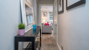 A hallway with a dining table, potted plants, and framed pictures on the walls. - Earl s Court Chelsea 2BR Modern Apt Walk to Tube (London)