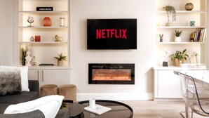 Ein modernes Wohnzimmer mit Kamin, einem Netflix-Schild und einer Bücherwand.