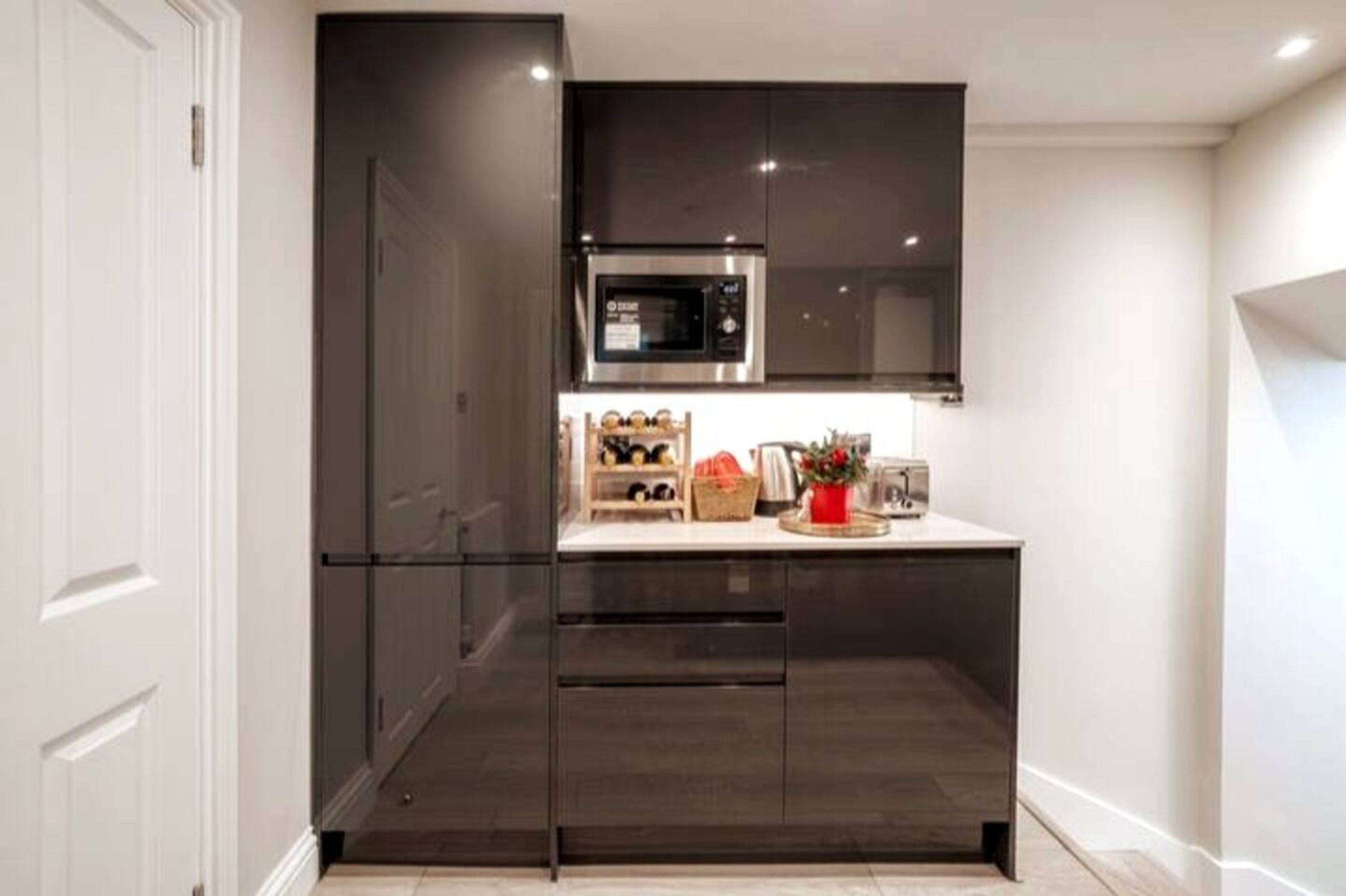 A modern kitchen with dark cabinetry, a built-in microwave, and a countertop with various items.