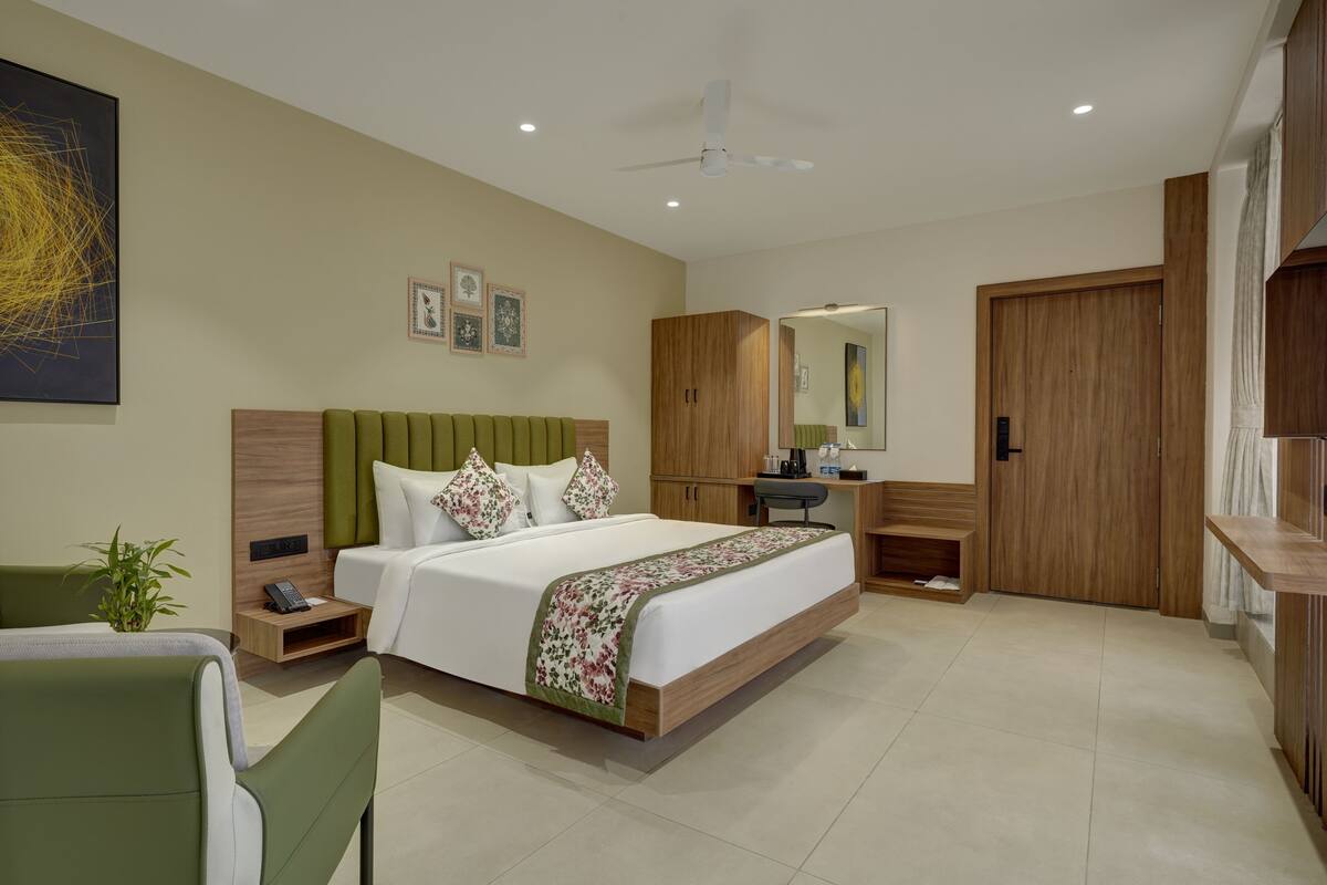 A modern hotel room with a large bed, a desk, a chair, a wardrobe, and a ceiling fan.