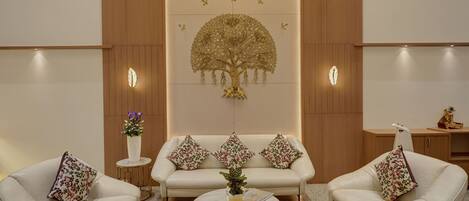 Een moderne woonkamer met een bank, twee fauteuils, een salontafel en een decoratief wandobject.
