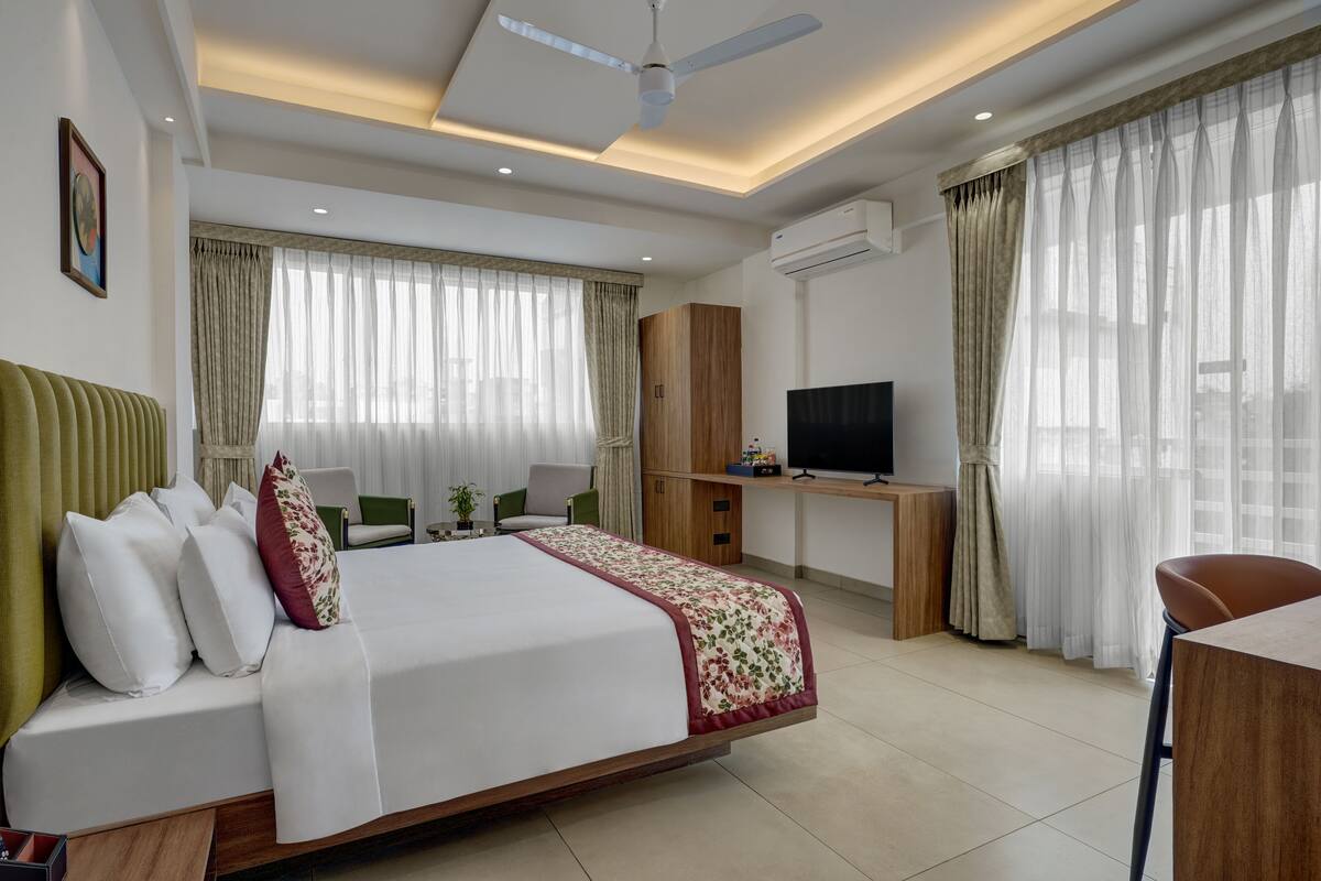 A hotel room with a bed, a desk, a television, and a ceiling fan.