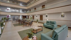 Eine mehrstöckige Hotelhalle mit Essbereich, Sitzgelegenheiten und einer Treppe.
