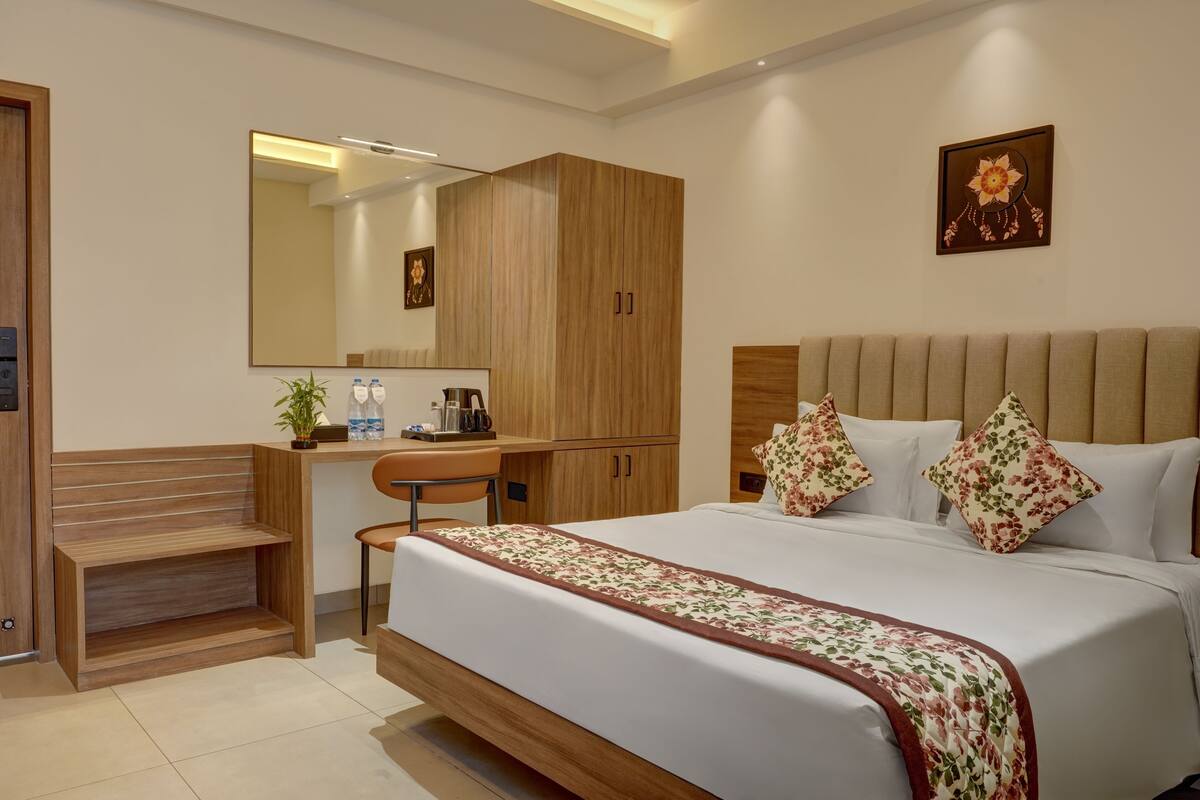 A bedroom with a bed, a desk, a chair, a wardrobe, and a mirror.