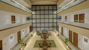 Eine großzügige Hotelhalle mit hoher Decke, mehreren Sitzbereichen und einer zentralen Wandgestaltung.