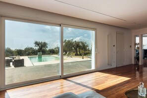 A spacious room with a large sliding glass door leading to an outdoor swimming pool area. - Pizzuta Country House (Noto)